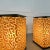 A pair of modern lighted tables or oversized lamps that give off a beautiful amber glow beneath the organic patterned...