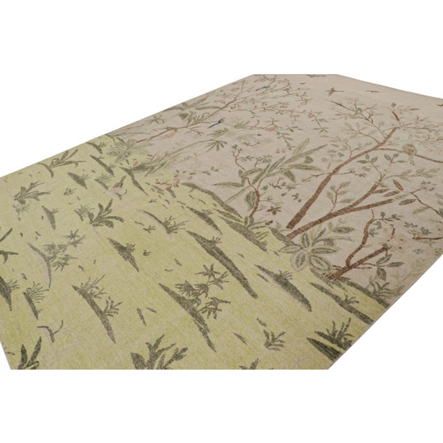 Hand-knotted in wool, this 10x14 modern rug, originating from India, features pictorials of depictions of greenery and...