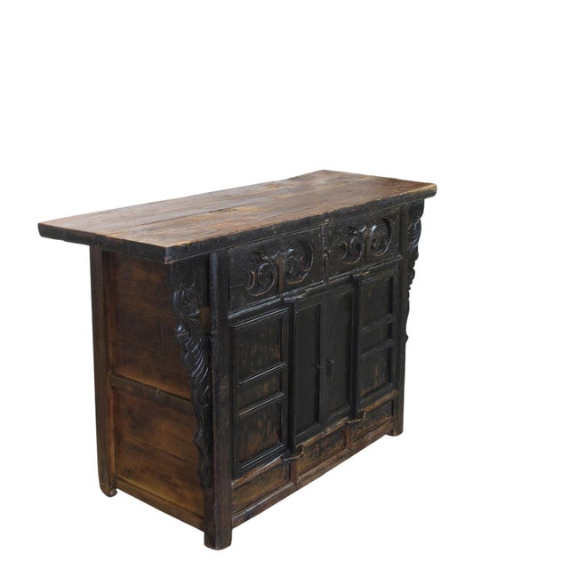 Crafted in 1826 from solid elm wood, this antique sideboard is distinguished by its deep, hand-carved scrolling motifs on...