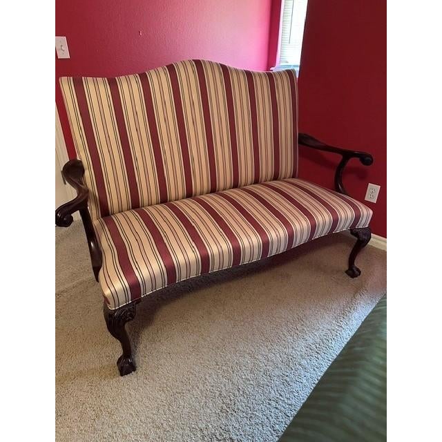 This piece, also known as a Georgian Style Loveseat, is an elegant settee featuring a classic camelback silhouette...
