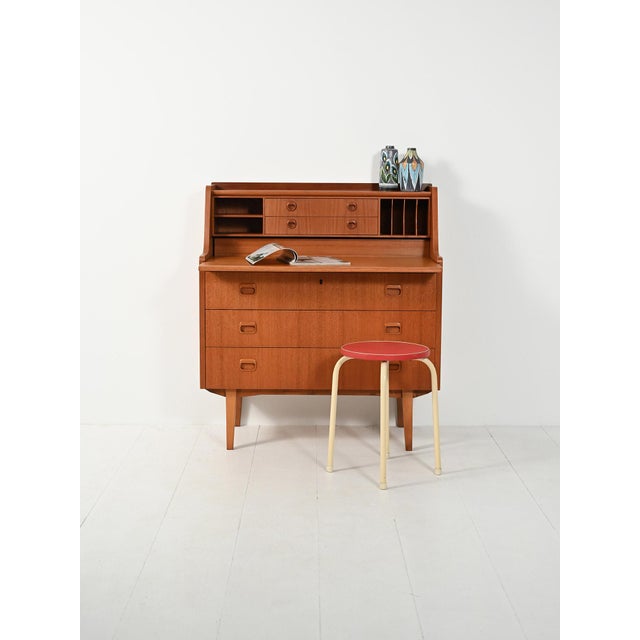 1960s teak secretary with a pull-out top, internal drawers, and paper dividers. Large carved handles, solid lines, and...
