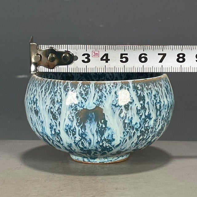 A charming Chinese ceramic tea cup or small bowl. The piece features a striking, highly textured "splash" or "flambé"...