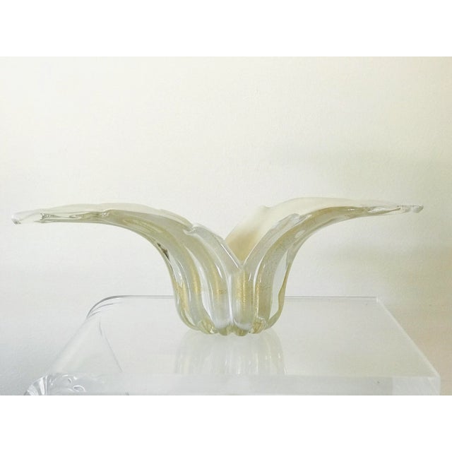 A ribbed glass bowl with flaring edges. The clear exterior is infused with gold flecks in the aventurine technique. The...