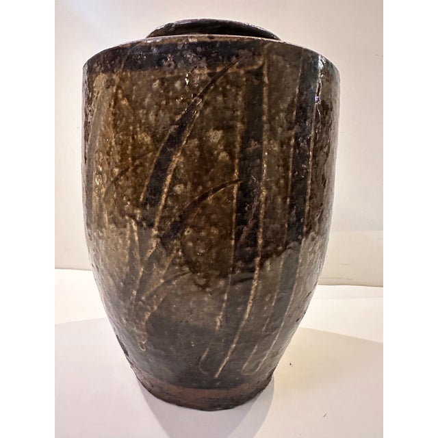 A vintage glazed ceramic vessel with a rounded shoulder and tapered body, finished in a rich brown and dark grey glaze...