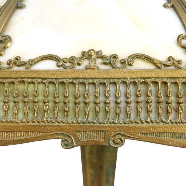 This antique table lamp, in the manner of Bradley & Hubbard School, features an eight-panel slag glass shade. The shade...