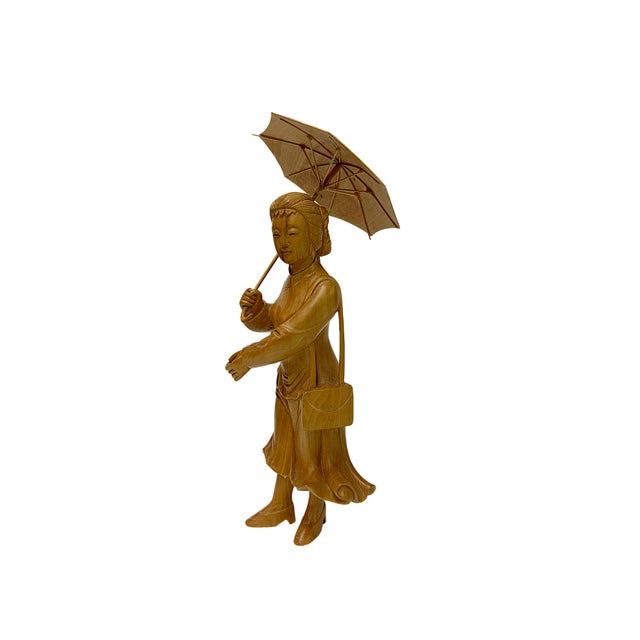 Exquisitely hand-carved from warm, honey-toned wood, this elegant figurine depicts a woman captured in mid-stride with a...