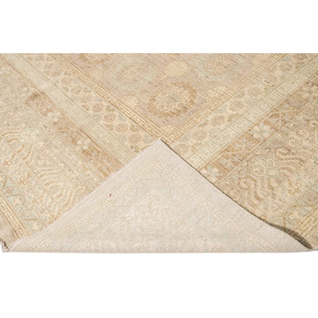 Beautiful modern oversize Khotan-style hand-knotted wool rug beige field. This Khotan-style rug has a blue frame and...