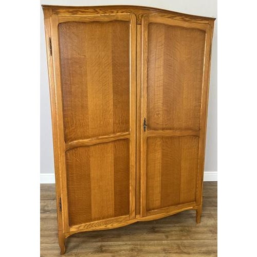A graceful Vintage French Louis wardrobe crafted from Oak, featuring two panelled doors, a warm natural finish and gently...