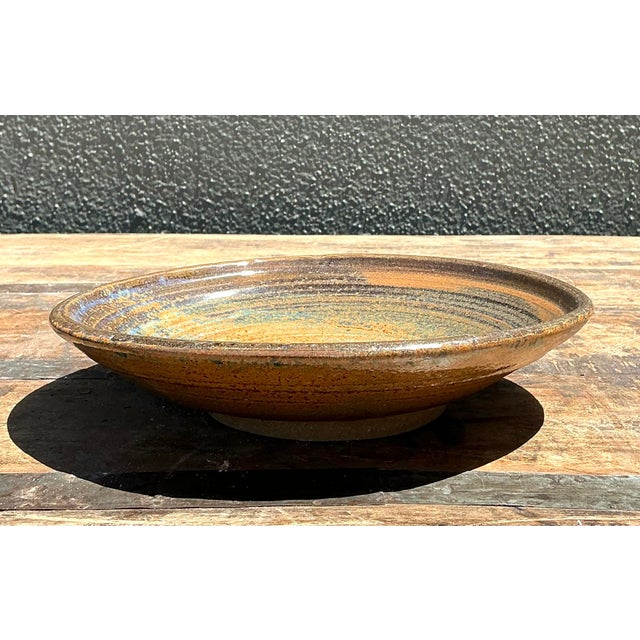 This vintage studio pottery bowl is a beautiful example of hand-thrown functional art, characterized by its low-profile,...