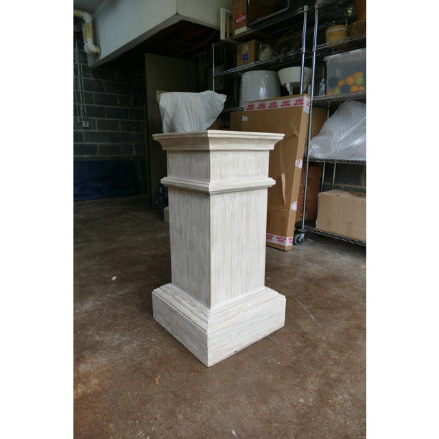 Distressed light wood pedestal that has been used for display.