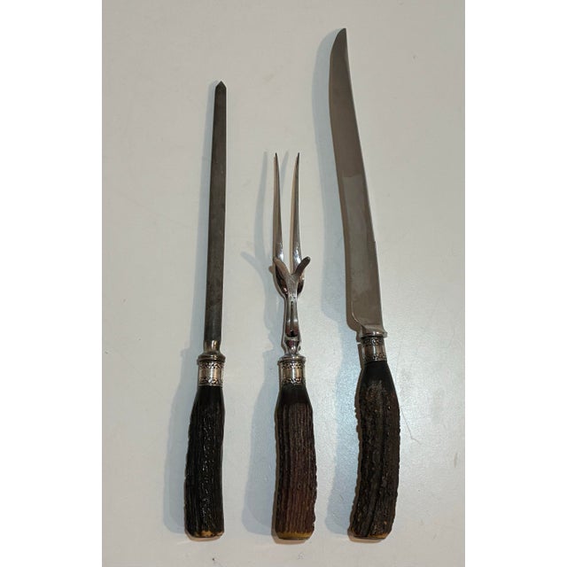 A three piece carving set with Stag Antler handles and Sterling Silver ferrules made in Sheffield, England, circa mid 20th...