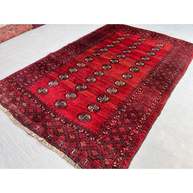 A vintage Afghan Ersari Turkmen rug in the classic Bokhara design — three columns of small quartered güls float on an...