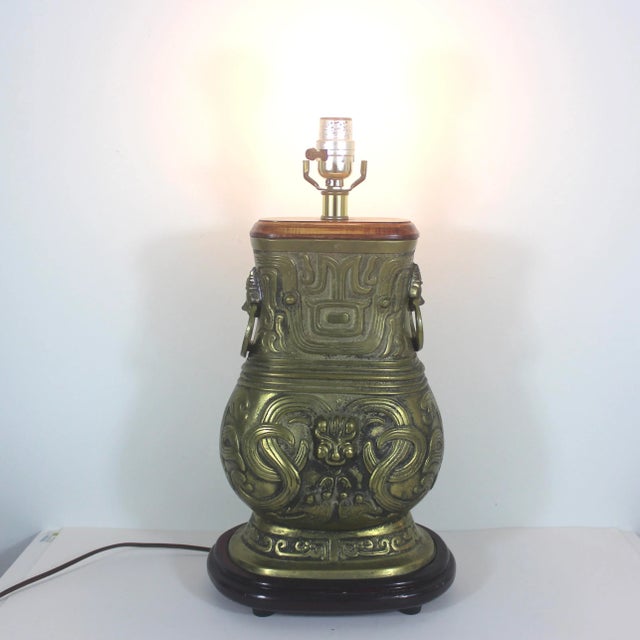 This is a very heavy Brass Chinese Hu vessel archaic urn that has been turned into a table lamp. The wood top is lighter...