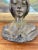 An early 20th-century Art Nouveau cast metal bust depicting a serene young woman, her hair softly framing her face. The...