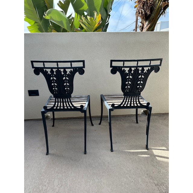 Elegant and architectural pair of vintage cast iron garden chairs featuring beautifully detailed lyre-form backs adorned...