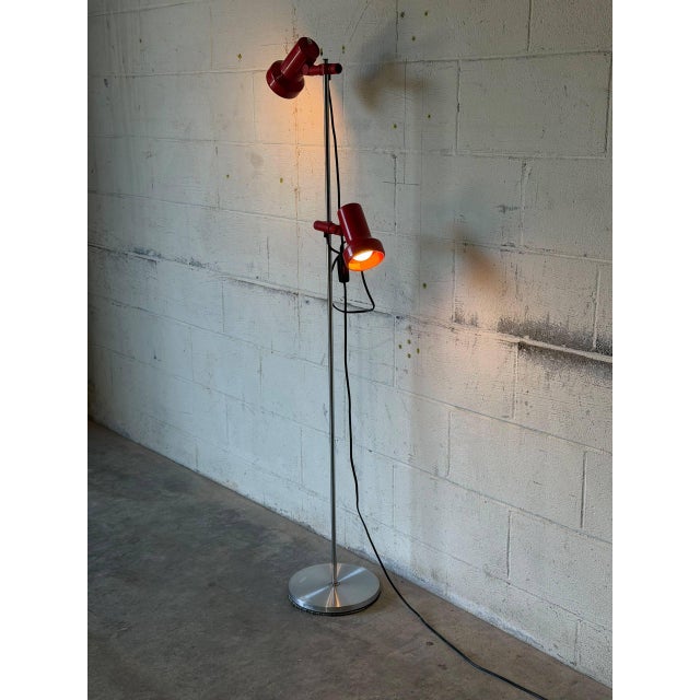 This vibrant floor lamp features two adjustable red shades mounted on a slim chrome standard. The sleek silhouette...