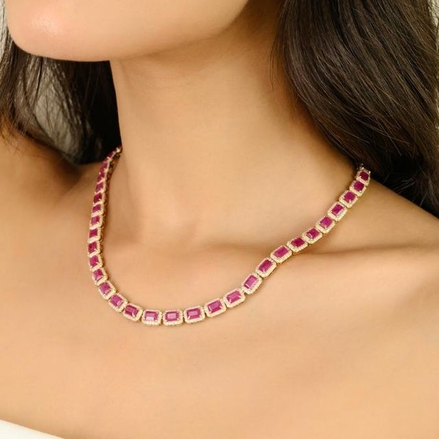 This luxurious tennis necklace features 48 octagon-cut natural rubies totaling 27.47 carats, all set in 14K yellow gold....