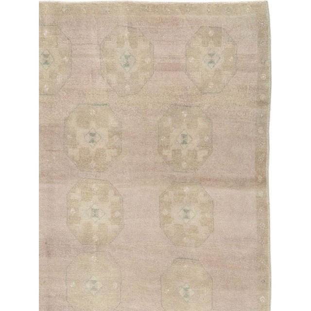 This Mid-20th century Turkish Anatolian accent rug presents a quiet, understated composition arranged across a softly...