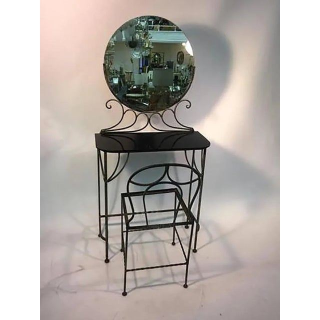 Graceful 1930s wrought iron vanity with round mirror and original black glass top. Original round mirror on top rests in...