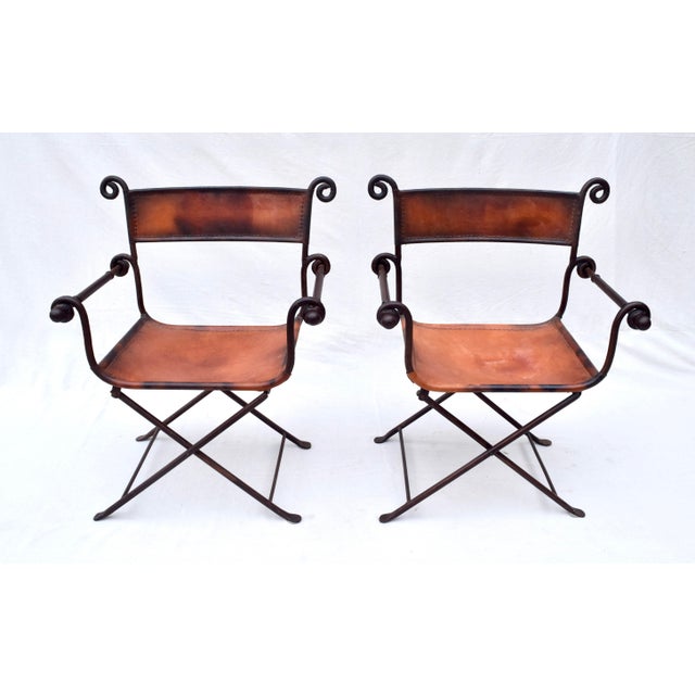 A striking pair of folding forged iron and leather chairs with exposed saddle stitching of the most substantial quality...
