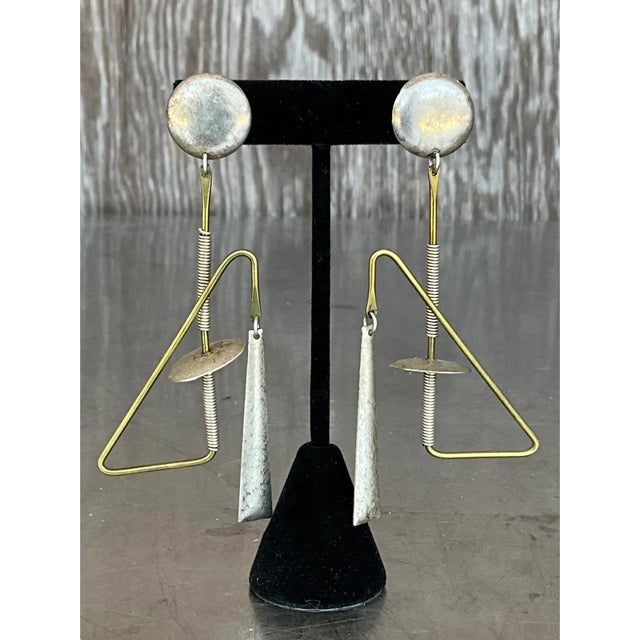 These vintage dangle earrings are kinetic, mobile-like compositions that read as miniature sculptures in motion. Each...