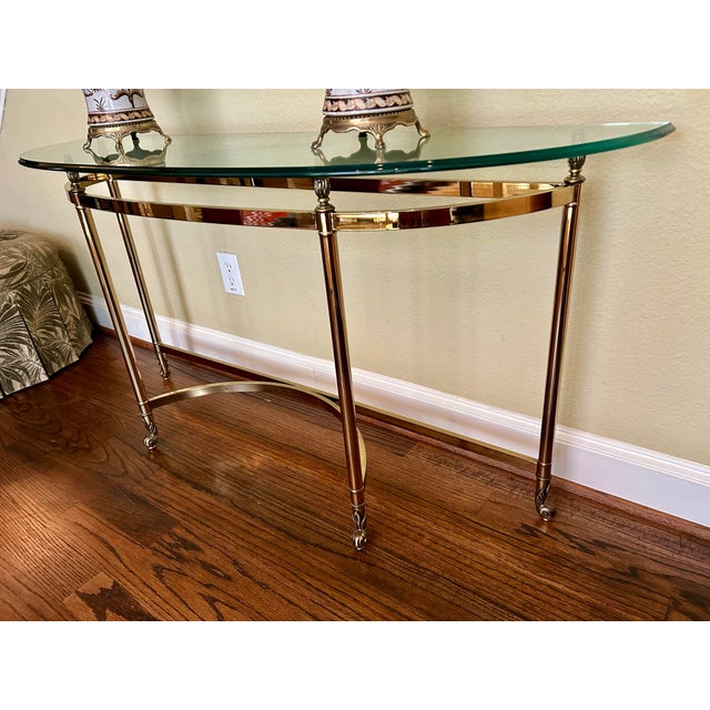 Beautiful French Regency style polished brass and glass console table by LaBarge. Lovely curves and details including...