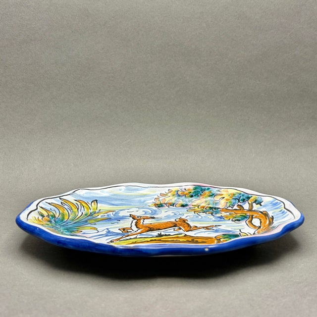 This mid-century hand-painted Spanish Talavera ceramic plate features a beautifully fluid scene of a leaping stag...