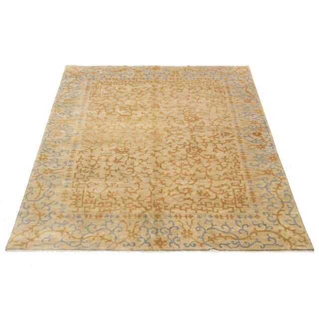 This beautifully hand-knotted Spanish Sino wool rug features a beige background adorned with blue and tan accents...