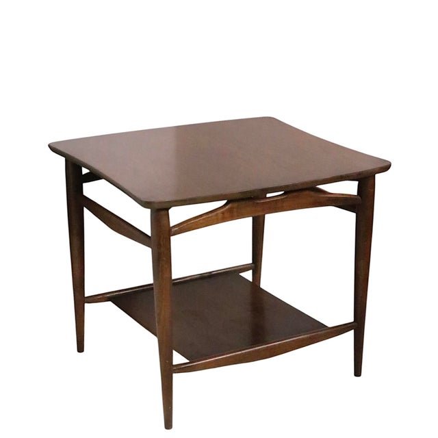 Classic pair of Mid Century end, or side, tables, having sculptural scoop end tops on tapered pole legs, with a smaller...