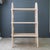 An antique handcrafted bucket bench turned bookshelf is painted in a pale peachy-pink tone, with a previous underlayer of...