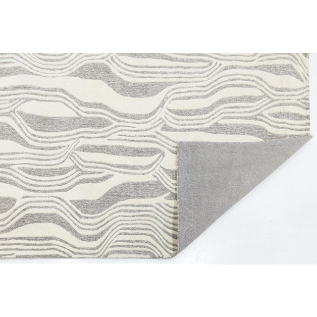Elevate your living space with this sophisticated modern hand-tufted rug, featuring a captivating organic wave pattern....