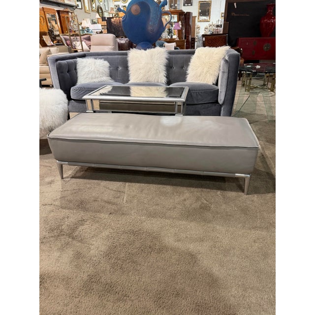 This sophisticated Roche Bobois bench features a sleek, elongated silhouette upholstered in smooth gray leather, elevated...