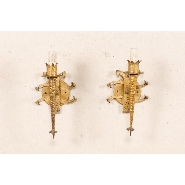 A pair of French single-light, forged-iron sconces in gold tone from the mid 20th century. This pair of vintage hand-...
