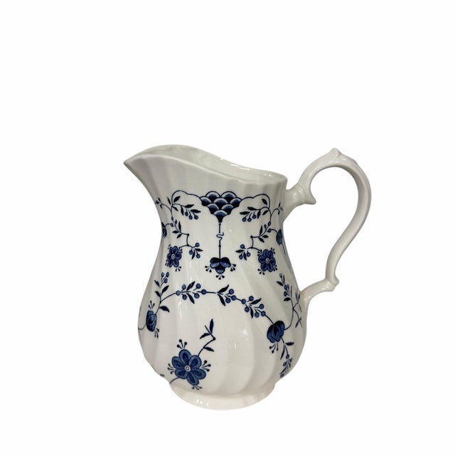 Vintage Churchill Finlandia milk pitcher, featuring a blue and white floral pattern and a swirling rim design....