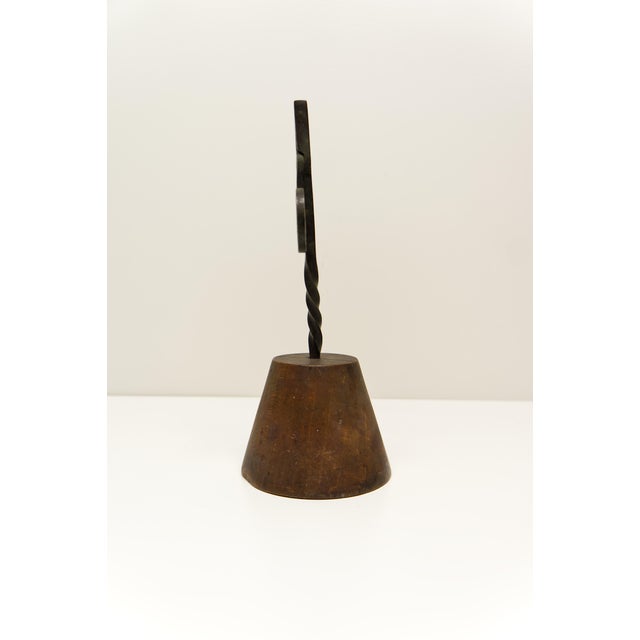 An early 19th-century wrought iron rushnip holder mounted on a wooden base is a charming example of early household...