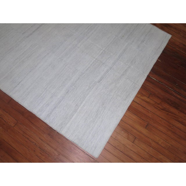 Intermediate size Persian Kilim in predominantly white. The piece is made from recycled cotton and goat hair material...