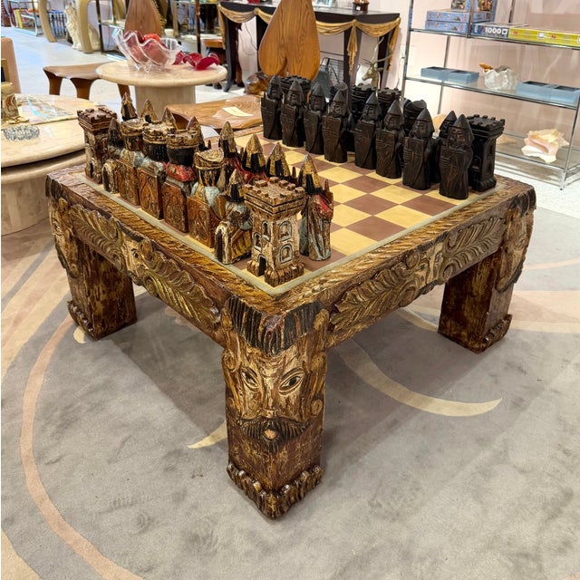 A spectacular European mid-century carved chess board coffee table with 32 carved wooden pieces. The legs of the table...