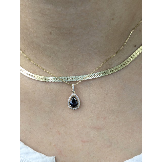 Sleek yet classic, this slide-style pendant showcases a 1.22-carat pear Ceylon sapphire, wrapped in a halo of earth-mined...