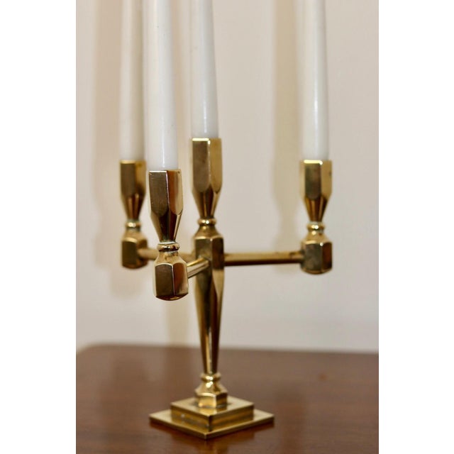 Made in Sweden. This exquisite four-arm candelabra, crafted from solid brass, is a design masterpiece produced by Gusum...