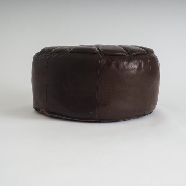 This vintage leather pouf is a striking piece that balances mid-century character with a soft, organic silhouette. The...