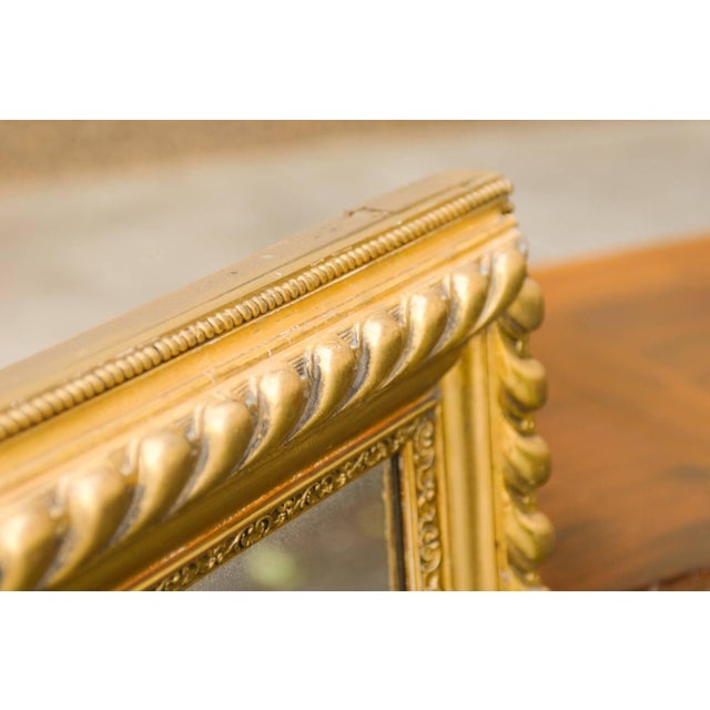 A French giltwood rectangular mirror with gadrooning from the early 20th century. This French mirror features a...