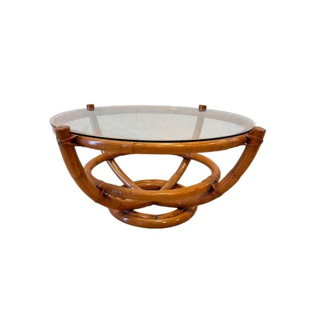 A fabulous vintage rattan coffee table dating to the 1970s, featuring a sculptural bamboo and rattan base topped with a...