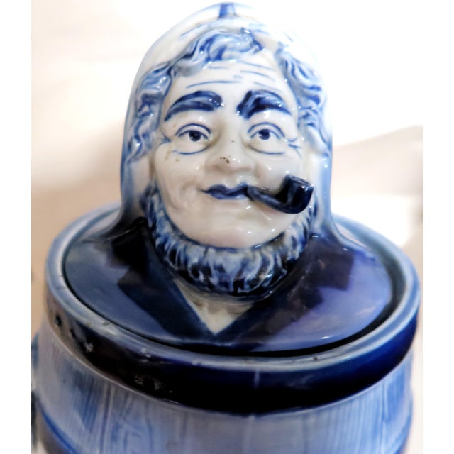 We offer this unusual Delft Porcelain Tobacco Box. It has a Barrel form with a figural lid. Wikipedia describes Delftware...