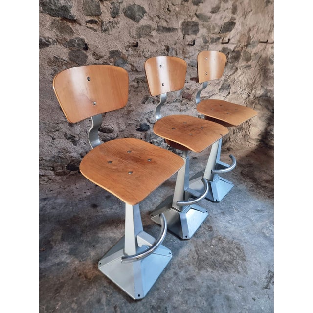 A set of three mid-century industrial swivel workshop chairs, characterised by their functional design and robust...