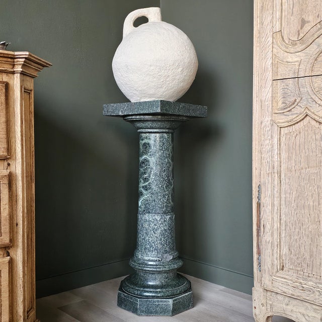 This refined marble pedestal, rendered in a striking deep green hue, is a versatile and timeless piece that enhances the...