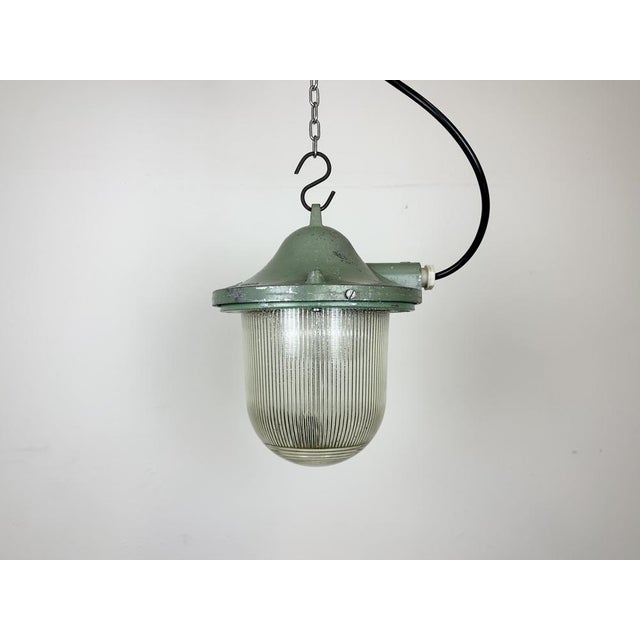 Green industrial lamp made by polam gdansk in poland during the 1960s. It features a cast aluminium body and a striped...