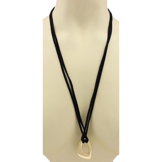 The product is an original 18k yellow gold pendant necklace with a suede cord. This fine jewelry piece exudes a stylish...