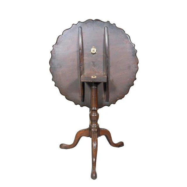 Hinged circular top with piecrust edge on a turned urn form support and ending on three cabriole legs with leaf carved knees.