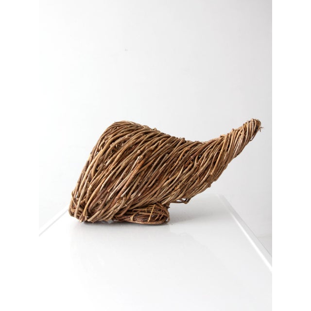 Vintage woven cornucopia basket with an oversized horn-shaped form made from layers of natural branches and vines. The...
