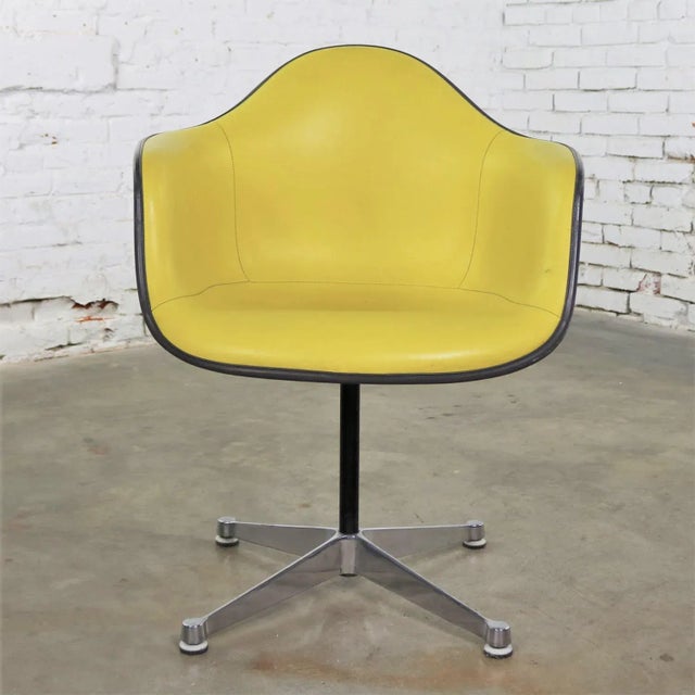 Iconic vintage Eames PAC, pivoting armchair on cast aluminum base, with yellow Naugahyde padded swivel seat on gray...